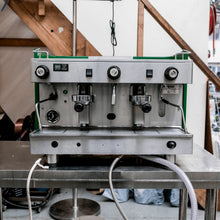 Load image into Gallery viewer, Commercial espresso machine on a metal stand with wooden staircase in the background